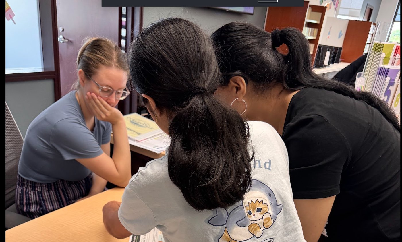 Sri leaning over a desk explaining her EcoServe project to a librarian at Colleyville Library